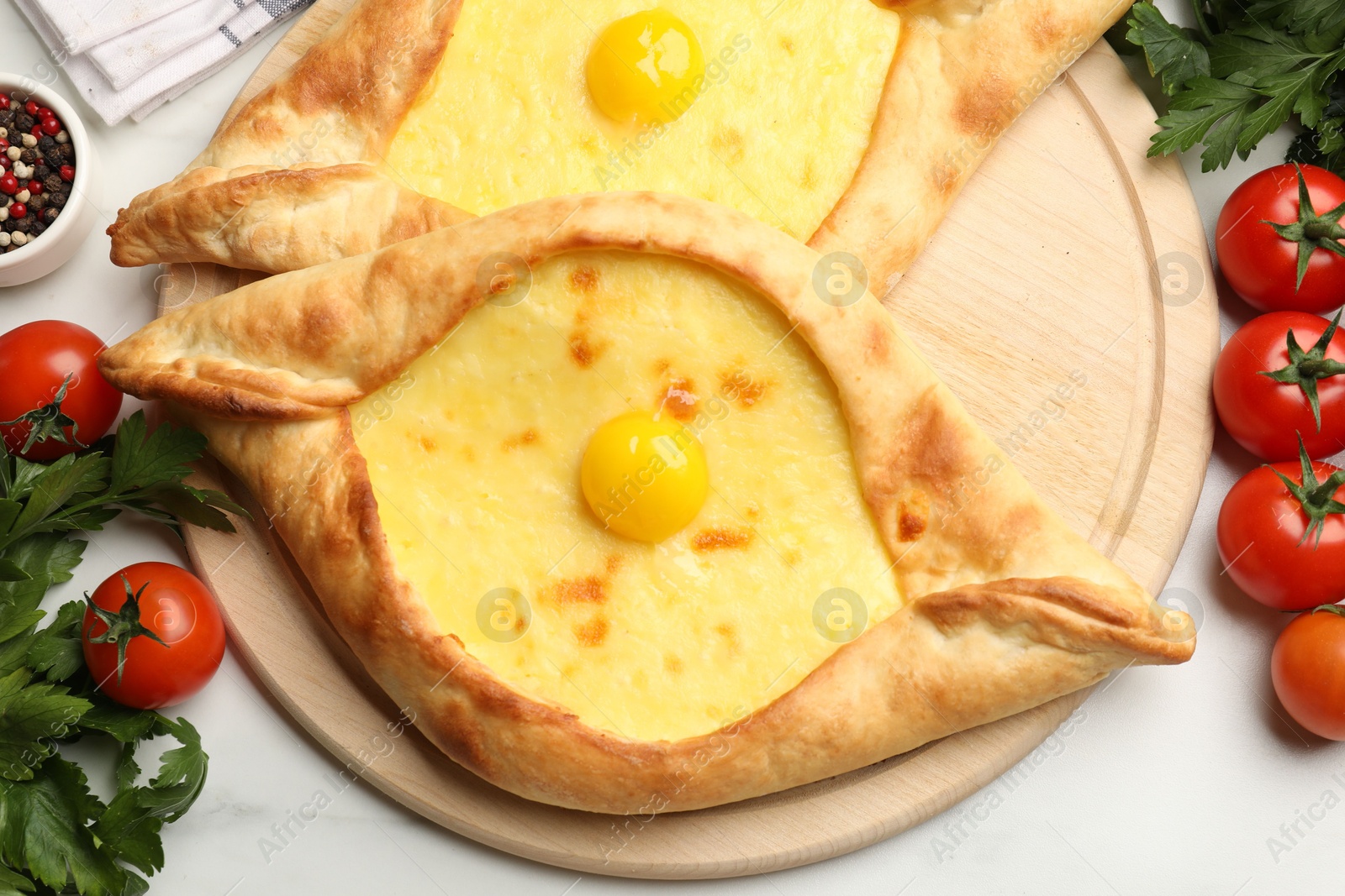 Tasty khachapuris with cheese, eggs, tomatoes, parsley and spices on white marble table, flat lay Photo of Tasty khachapuris with cheese, eggs, tomatoes, parsley and spices on white marble table, flat lay