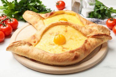 Photo of Tasty khachapuris with cheese, eggs, tomatoes, parsley and spices on white marble table, closeup