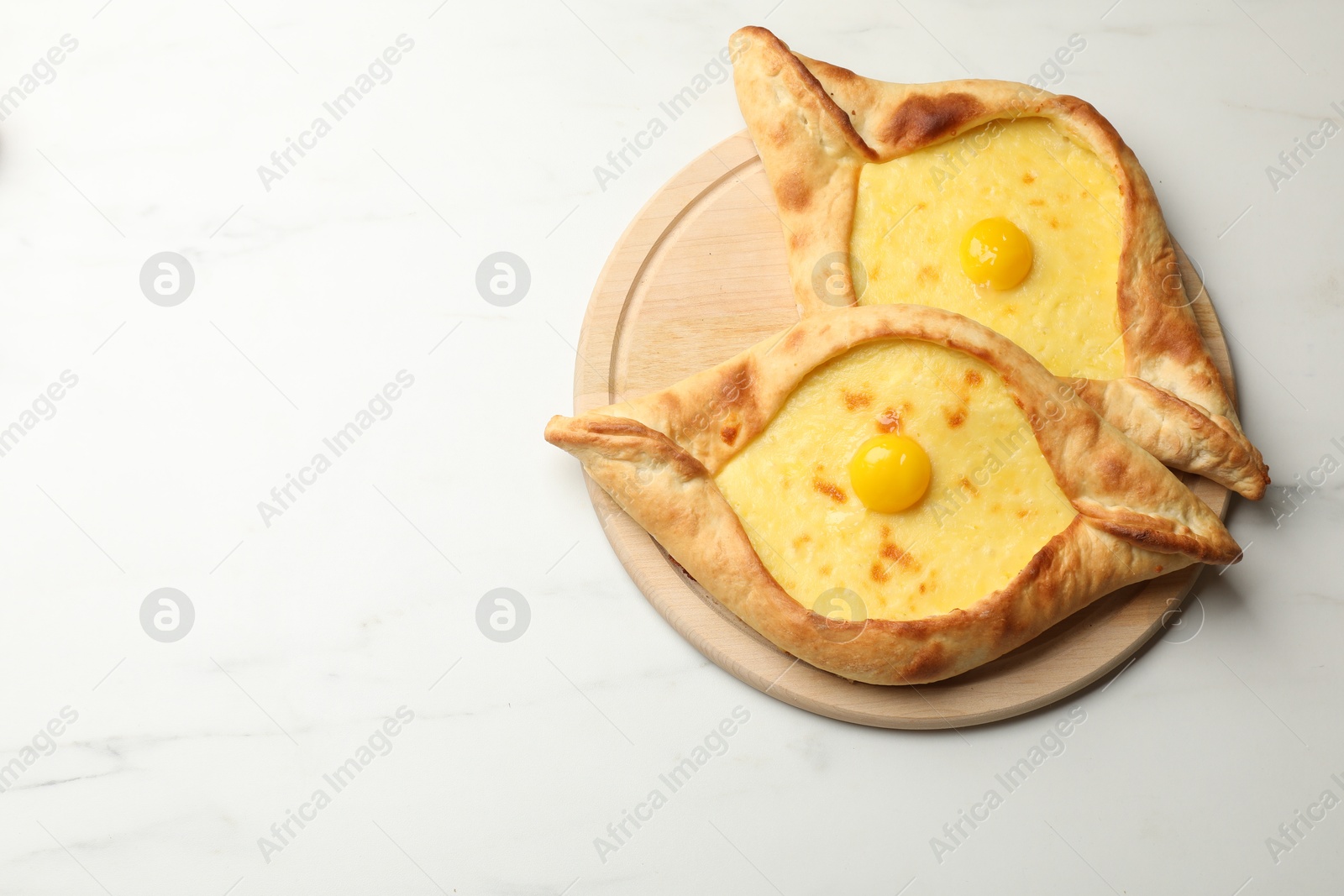 Tasty khachapuris with cheese and eggs on white marble table, top view. Space for text Photo of Tasty khachapuris with cheese and eggs on white marble table, top view. Space for text