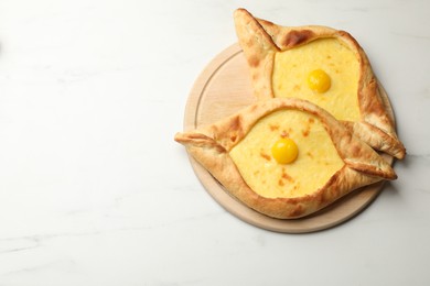 Photo of Tasty khachapuris with cheese and eggs on white marble table, top view. Space for text