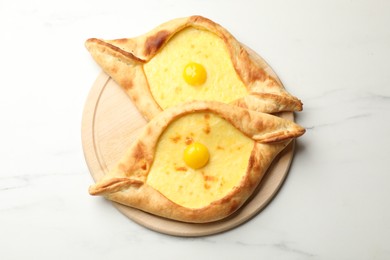 Photo of Tasty khachapuris with cheese and eggs on white marble table, top view