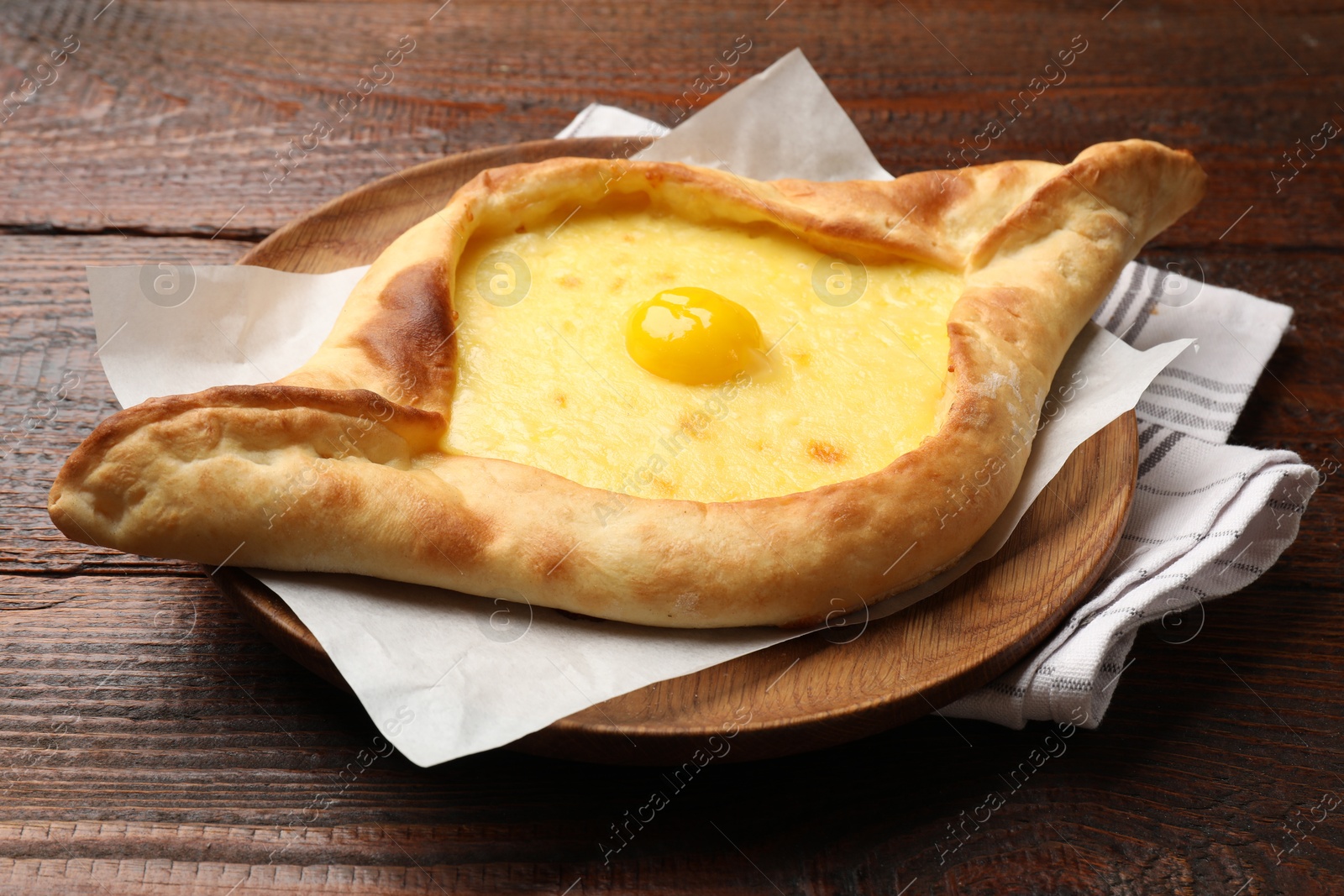 Photo of Tasty khachapuri with cheese and egg on wooden table, closeup