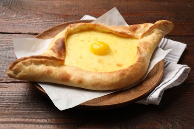 Photo of Tasty khachapuri with cheese and egg on wooden table, closeup