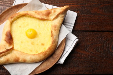 Photo of Tasty khachapuri with cheese and egg on wooden table, top view. Space for text