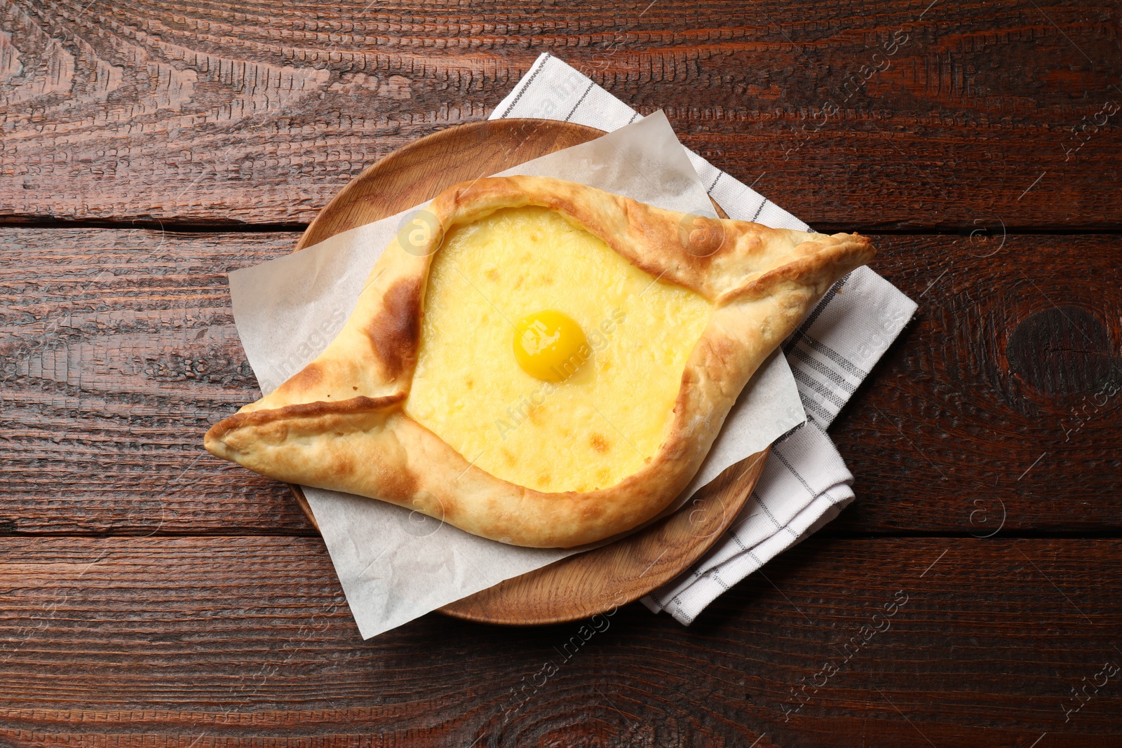Photo of Tasty khachapuri with cheese and egg on wooden table, top view