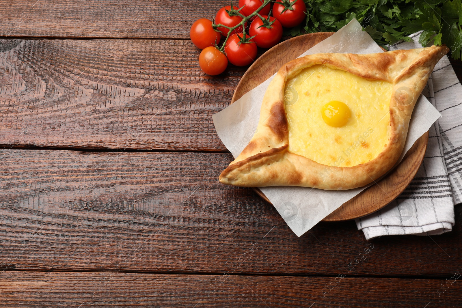 Tasty khachapuri with cheese, egg, tomatoes and parsley on wooden table, flat lay. Space for text Photo of Tasty khachapuri with cheese, egg, tomatoes and parsley on wooden table, flat lay. Space for text
