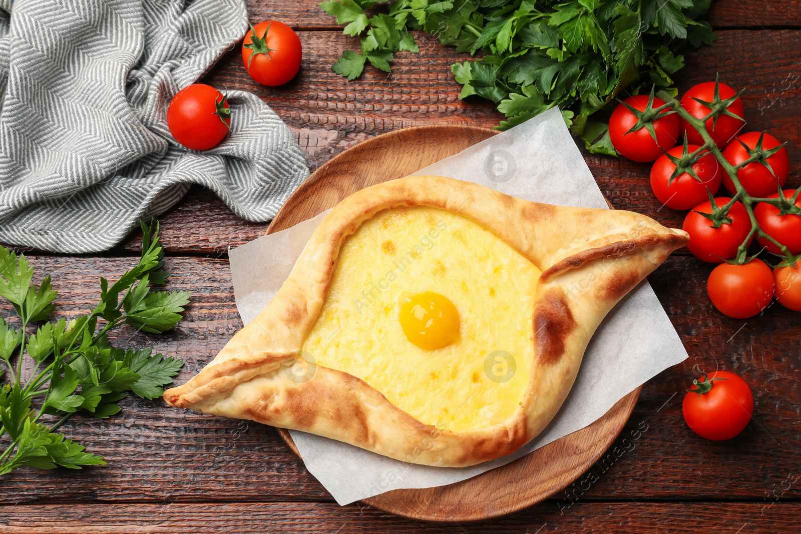 Tasty khachapuri with cheese, egg, tomatoes and parsley on wooden table, flat lay Photo of Tasty khachapuri with cheese, egg, tomatoes and parsley on wooden table, flat lay