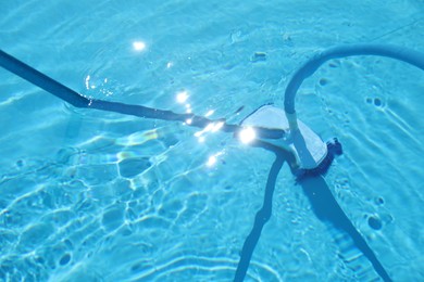 Photo of Cleaning outdoor pool with underwater vacuum, closeup
