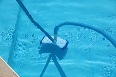 Photo of Cleaning outdoor pool with underwater vacuum, closeup