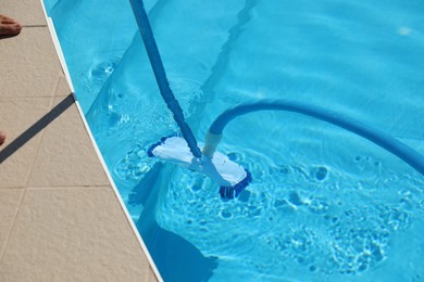 Photo of Cleaning outdoor pool with underwater vacuum, closeup