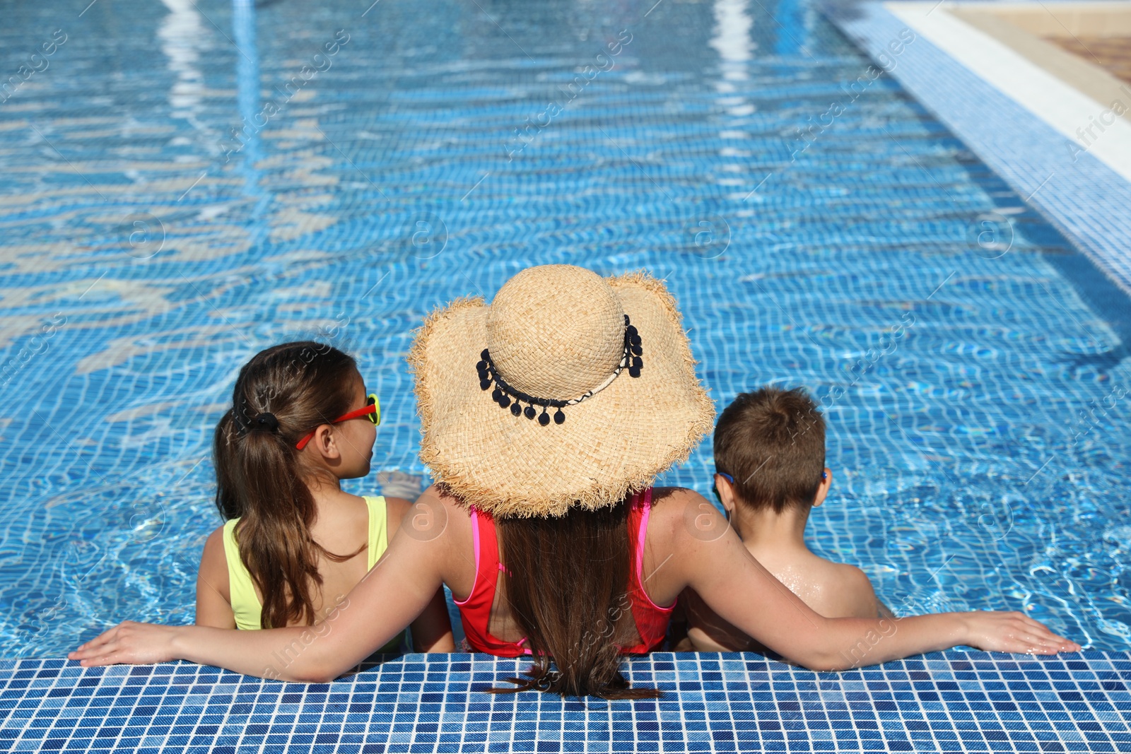 Woman with her children in swimming pool, back view. Summer vacation Photo of Woman with her children in swimming pool, back view. Summer vacation