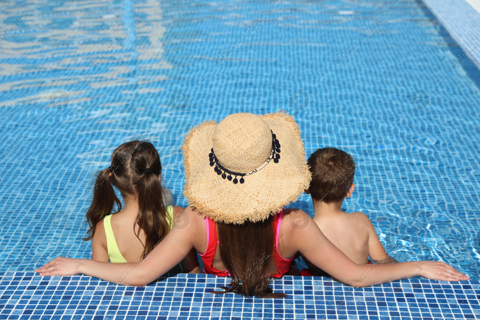 Woman with her children in swimming pool, back view. Summer vacation Photo of Woman with her children in swimming pool, back view. Summer vacation