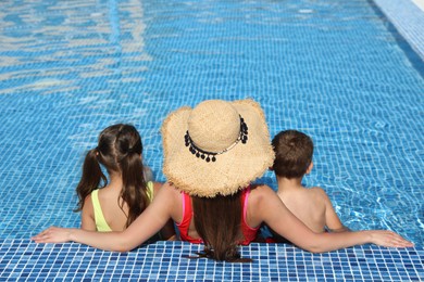 Photo of Woman with her children in swimming pool, back view. Summer vacation