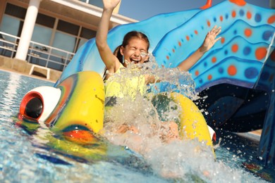 Photo of Happy girl on slide at water park. Summer vacation