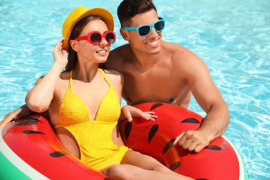 Photo of Happy couple with inflatable ring in swimming pool. Summer vacation