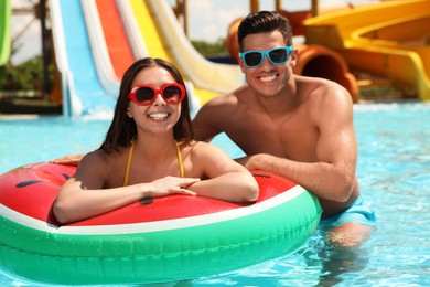Photo of Happy couple with inflatable ring at water park. Summer vacation