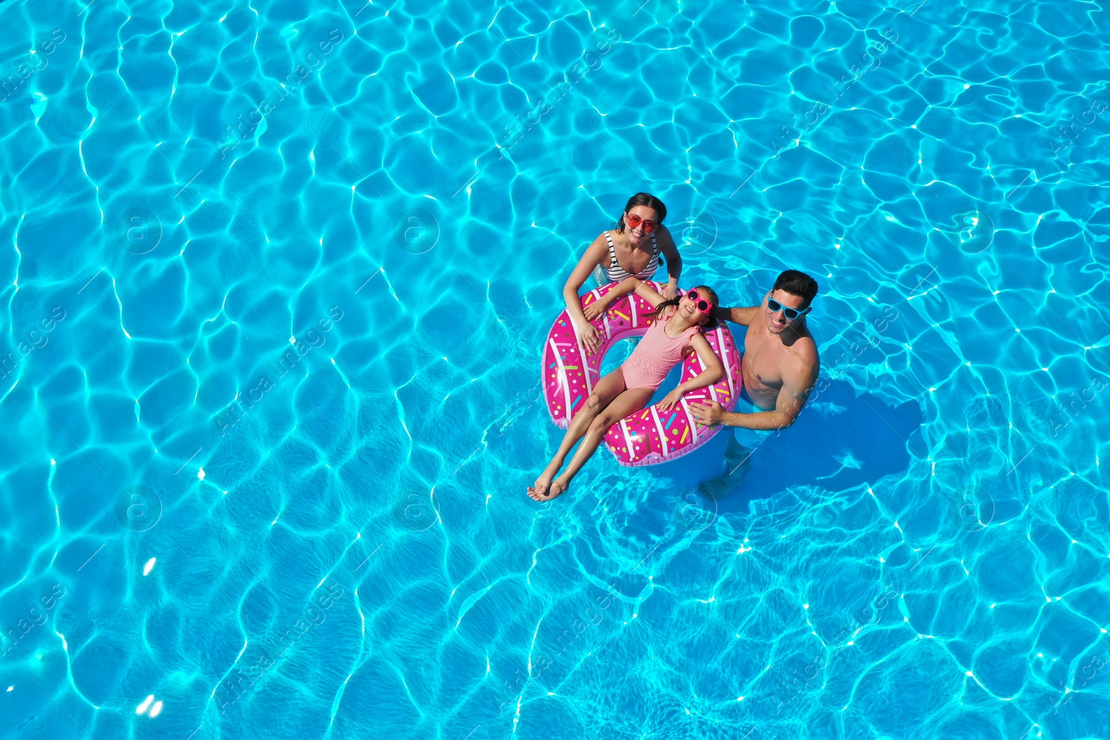 Happy family with inflatable ring in swimming pool. Summer vacation Photo of Happy family with inflatable ring in swimming pool. Summer vacation