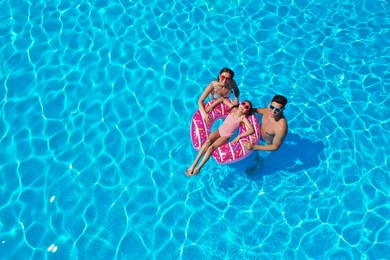 Photo of Happy family with inflatable ring in swimming pool. Summer vacation