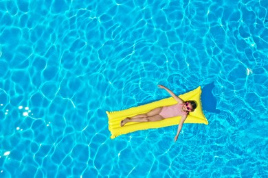 Photo of Girl on inflatable mattress in swimming pool, top view. Summer vacation