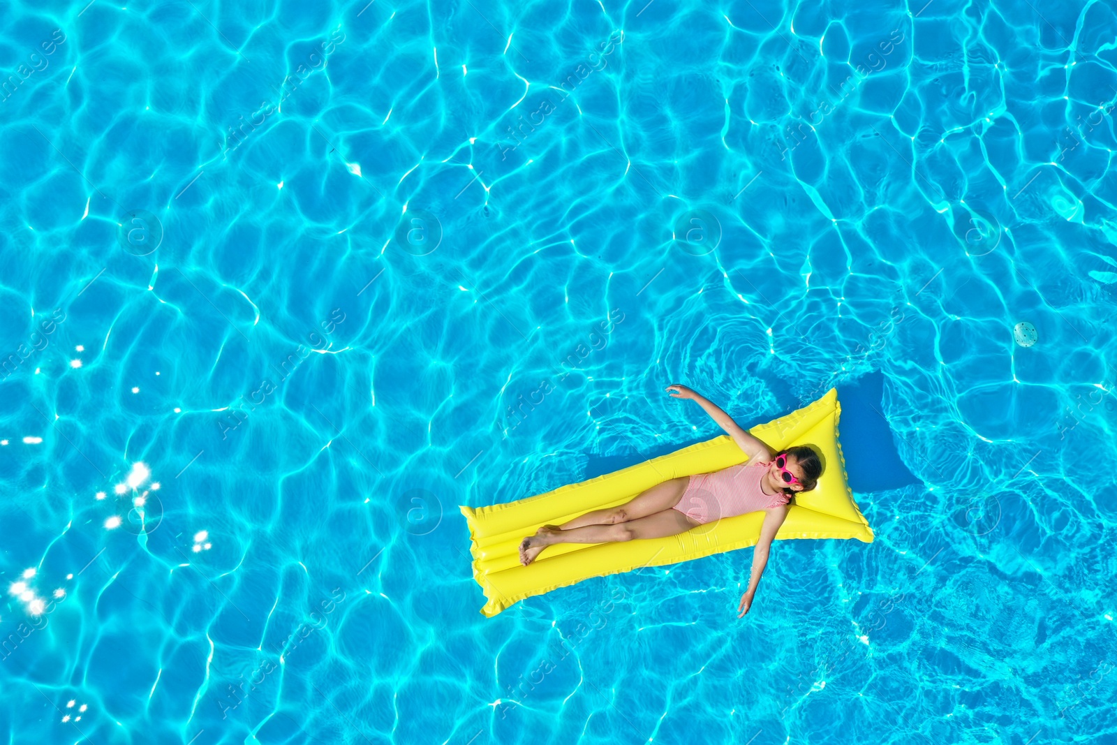 Girl on inflatable mattress in swimming pool, top view. Summer vacation Photo of Girl on inflatable mattress in swimming pool, top view. Summer vacation