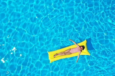 Photo of Girl on inflatable mattress in swimming pool, top view. Summer vacation