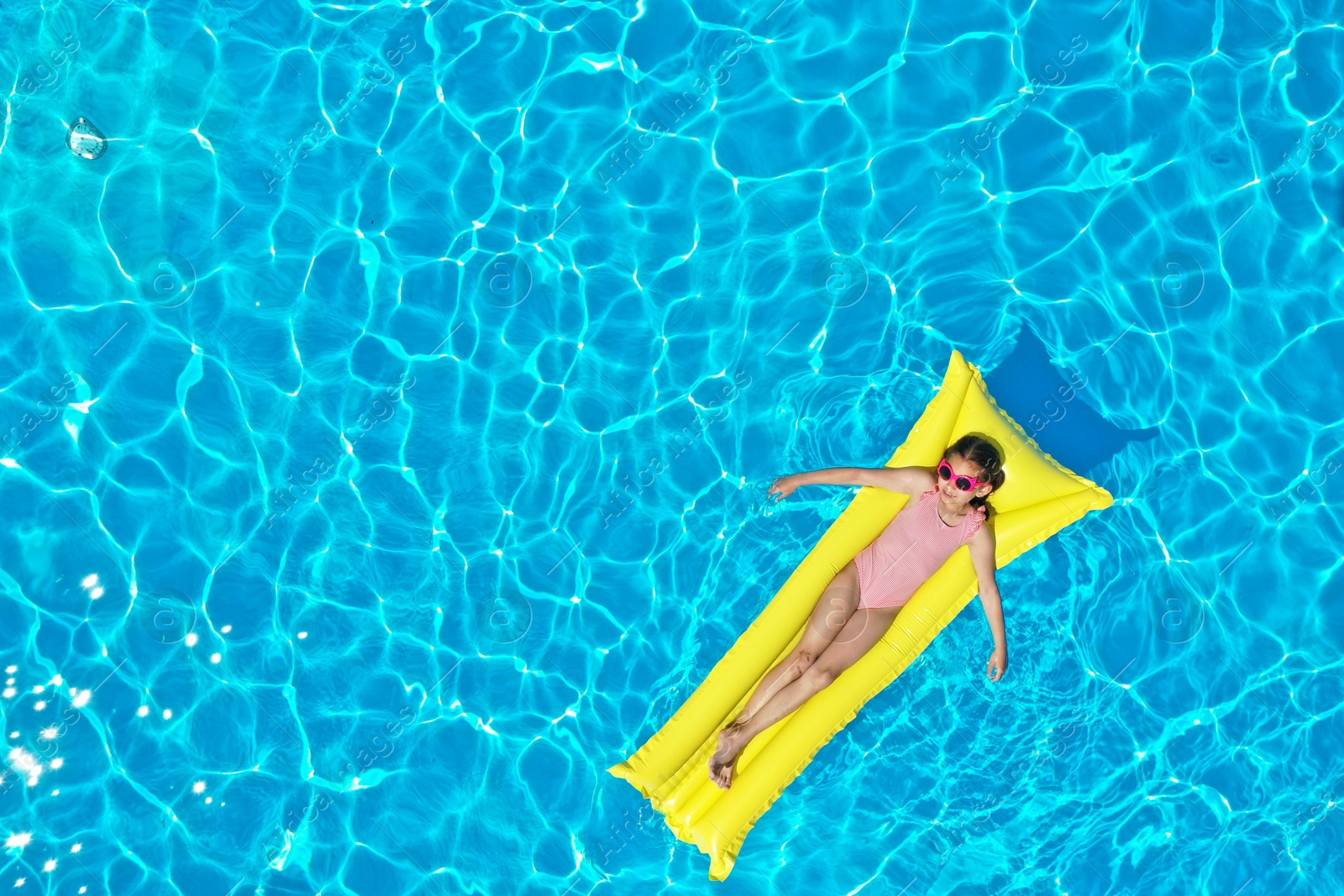 Girl on inflatable mattress in swimming pool, top view. Summer vacation Photo of Girl on inflatable mattress in swimming pool, top view. Summer vacation
