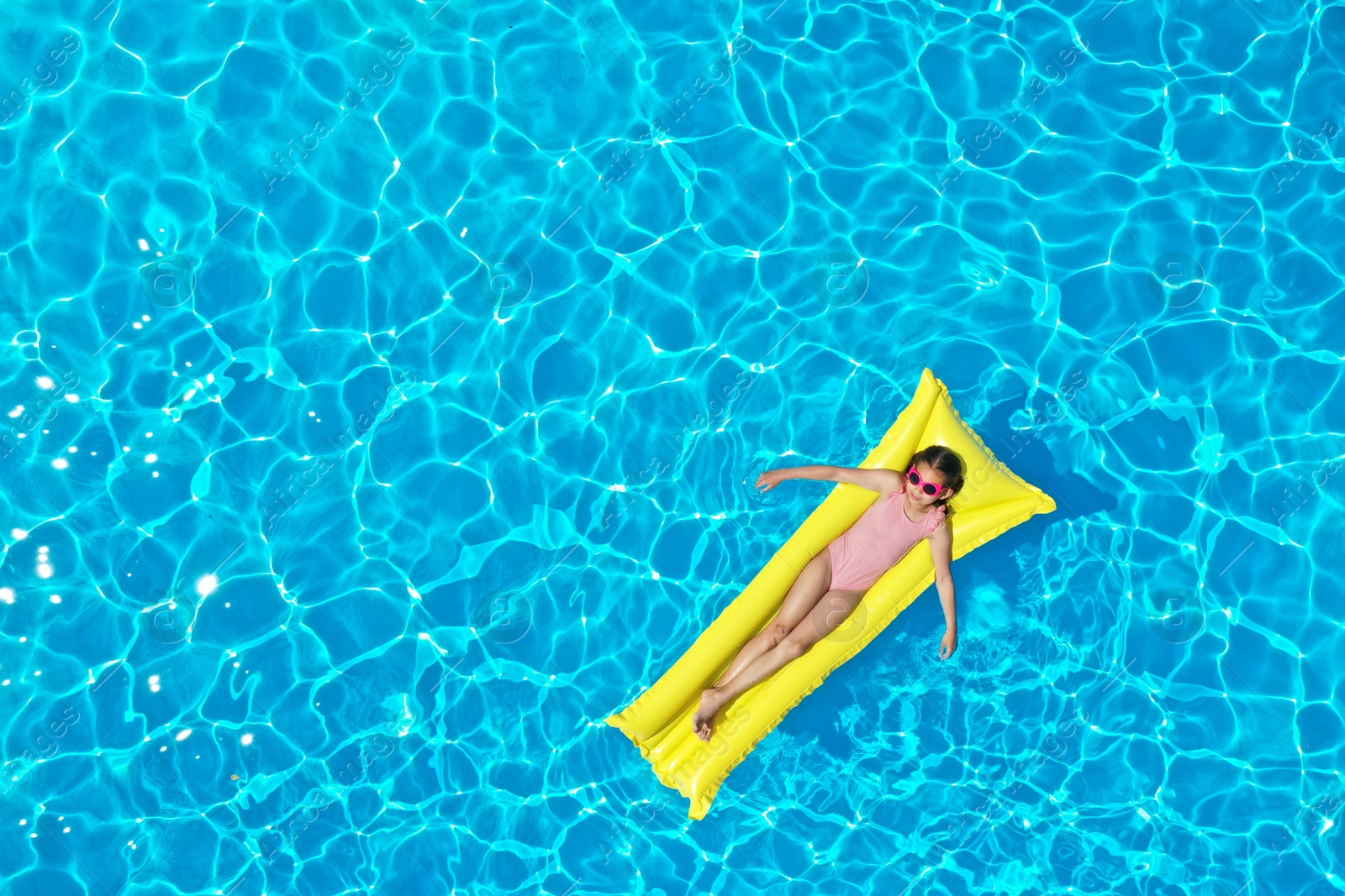 Girl on inflatable mattress in swimming pool, top view. Summer vacation Photo of Girl on inflatable mattress in swimming pool, top view. Summer vacation