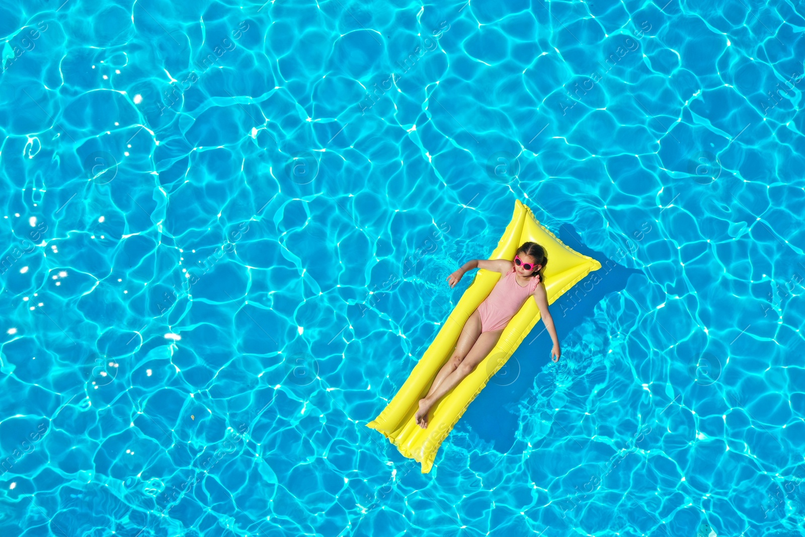 Girl on inflatable mattress in swimming pool, top view. Summer vacation Photo of Girl on inflatable mattress in swimming pool, top view. Summer vacation