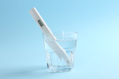 Photo of Nitrate tester in glass of water on light blue background