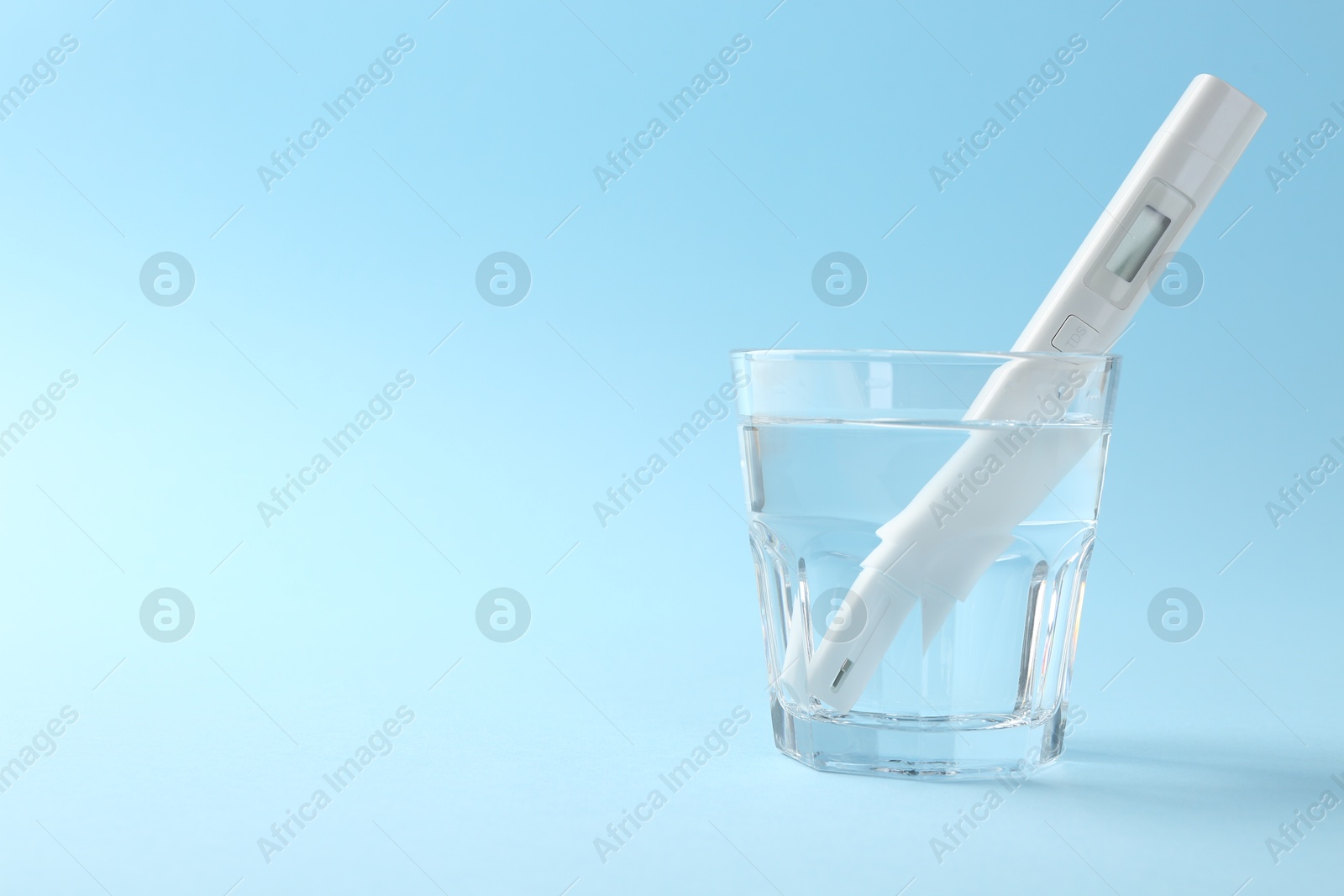 Nitrate tester in glass of water on light blue background, space for text Photo of Nitrate tester in glass of water on light blue background, space for text