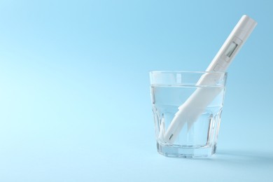 Photo of Nitrate tester in glass of water on light blue background, space for text