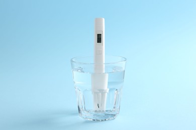 Photo of Nitrate tester in glass of water on light blue background, closeup