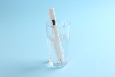 Photo of Nitrate tester in glass of water on light blue background
