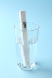 Photo of Nitrate tester in glass of water on light blue background, closeup