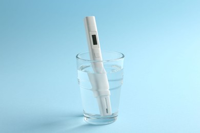 Photo of Nitrate tester in glass of water on light blue background