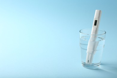 Photo of Nitrate tester in glass of water on light blue background, space for text