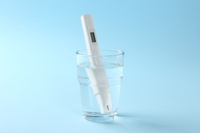 Photo of Nitrate tester in glass of water on light blue background
