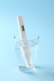 Photo of Nitrate tester in glass of water on light blue background, closeup
