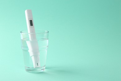 Photo of Nitrate tester in glass of water on turquoise background, space for text