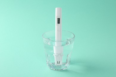 Photo of Nitrate tester in glass of water on turquoise background, closeup
