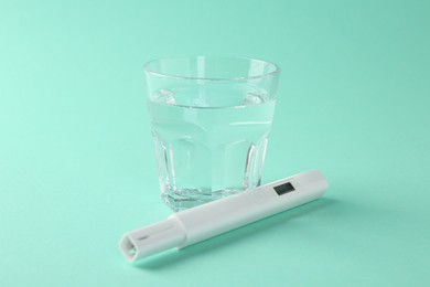 Photo of Nitrate tester and glass of water on turquoise background, closeup