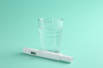 Photo of Nitrate tester and glass of water on turquoise background, closeup