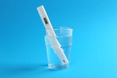 Photo of Nitrate tester in glass of water on light blue background