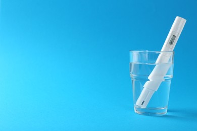 Photo of Nitrate tester in glass of water on light blue background, space for text