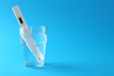 Photo of Nitrate tester in glass of water on light blue background, space for text