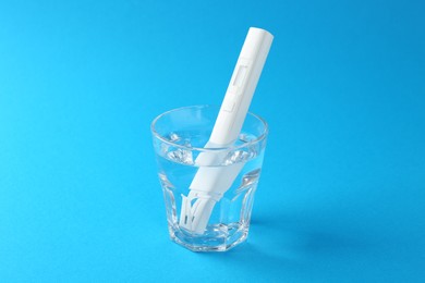 Photo of Nitrate tester in glass of water on light blue background