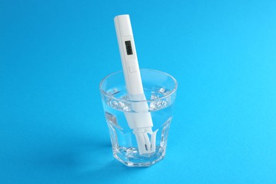 Photo of Nitrate tester in glass of water on light blue background, closeup