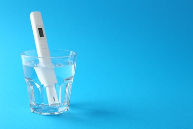 Photo of Nitrate tester in glass of water on light blue background, space for text