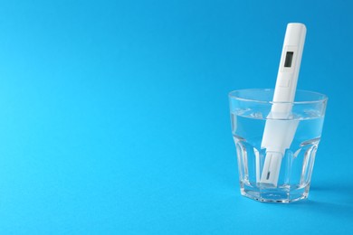 Photo of Nitrate tester in glass of water on light blue background, space for text