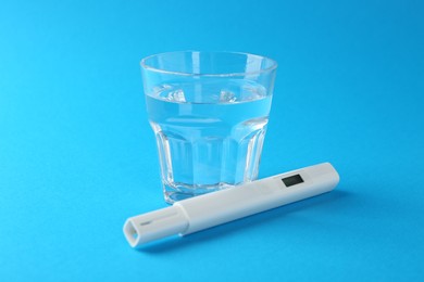 Photo of Nitrate tester and glass of water on light blue background, closeup